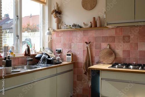 Cozy kitchen interior with pink tiles and sunlight photo