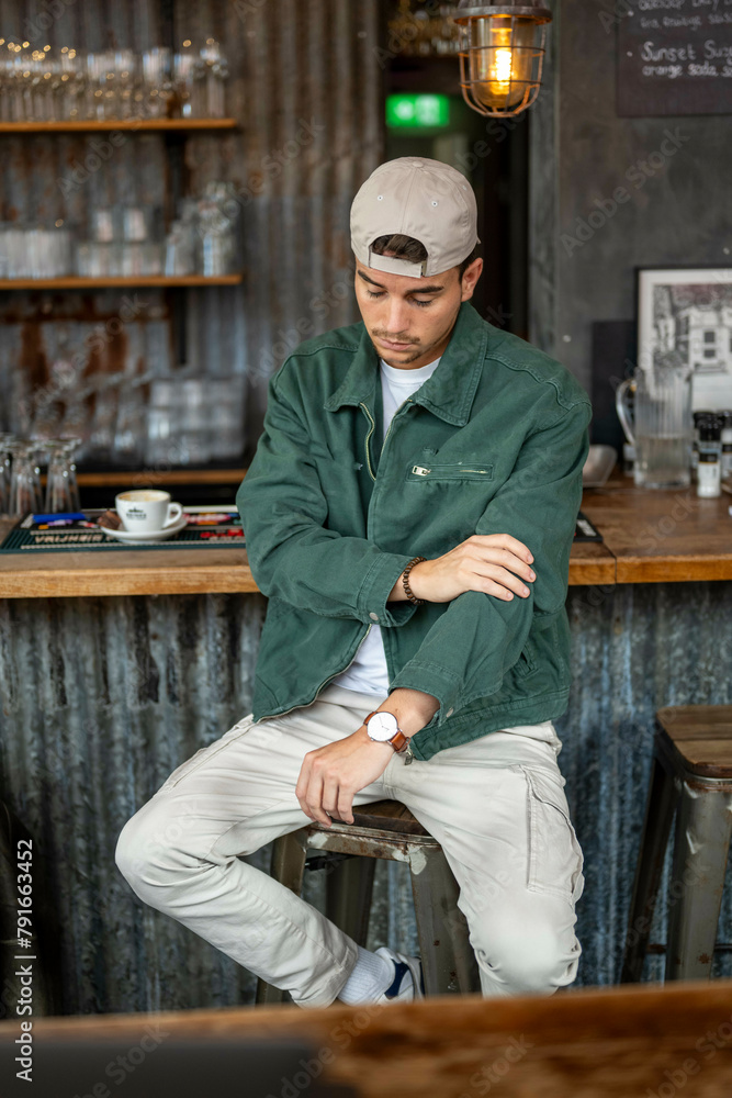 Man sitting on a bar stool in a casual outfit Man sitting on a bar stool in a casual outfit