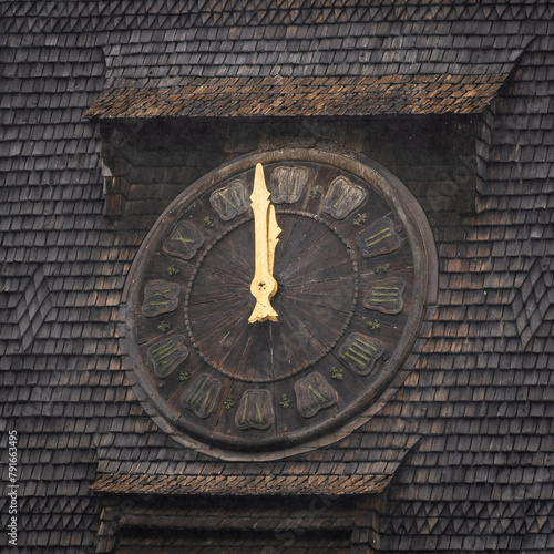 Old clock with a wooden face. A shingle roof background. 