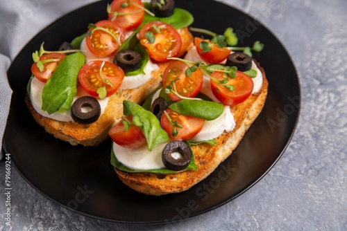 Bruschetta with cherry tomatoes, mozzarella cheese, olives and herbs. Italian Cuisine. Healthy eating.