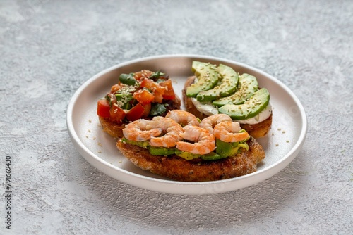 Bruschetta with avocado, shrimp, tomatoes, guacamole, cream cheese and herbs. Healthy eating.