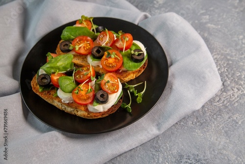 Bruschetta with cherry tomatoes, mozzarella cheese, olives and herbs. Italian Cuisine. Healthy eating.