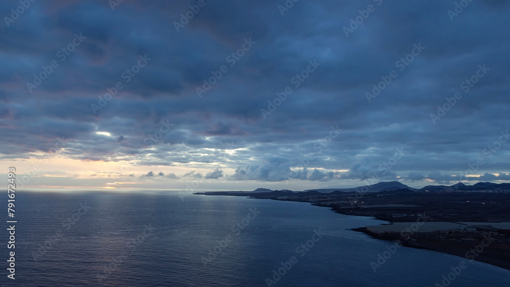 Dusk evening sea view with rain clouds and setting sun. Mountain coast of the ocean. Weather on summer vacations. Red Mountain lookout, Tenerife, Santa Cruz de Tenerife, Spain