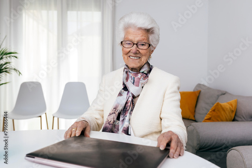 Elderly woman with laptop at home showing joy in work photo