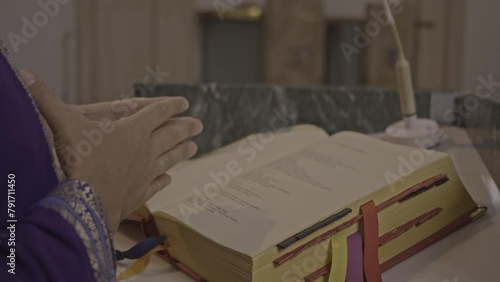 Christian priest preaching psalmbook in church during Holy Mass close up. Pastor standing on podium in Catholic cathedral, reading Bible and praying close view photo