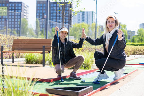 mother and daughter playing mini golf, children enjoying summer vacation photo