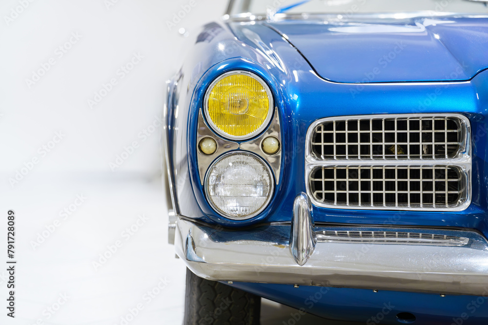 Fototapeta premium Front view of a blue vintage car. Classic car. Headlights. White background.