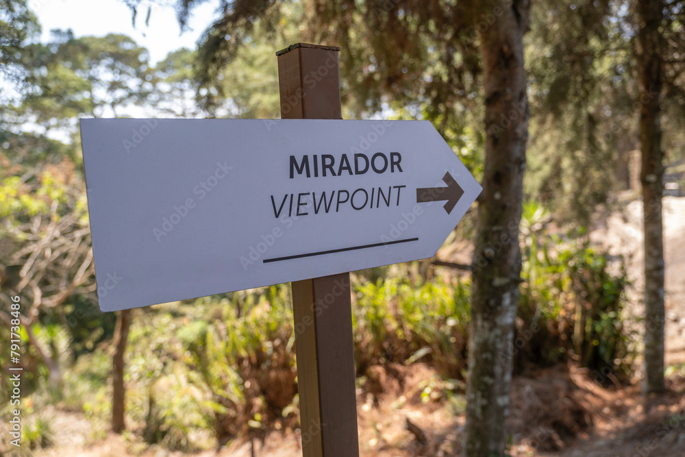 Sign in English and Spanish viewpoint and direction arrow on a trail in El Boqueron National Park forest in El Salvador.