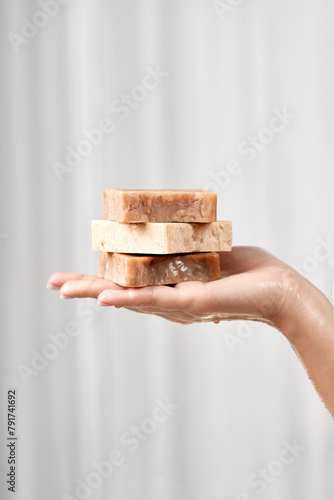a woman's hand holds a soap, natural handmade soap