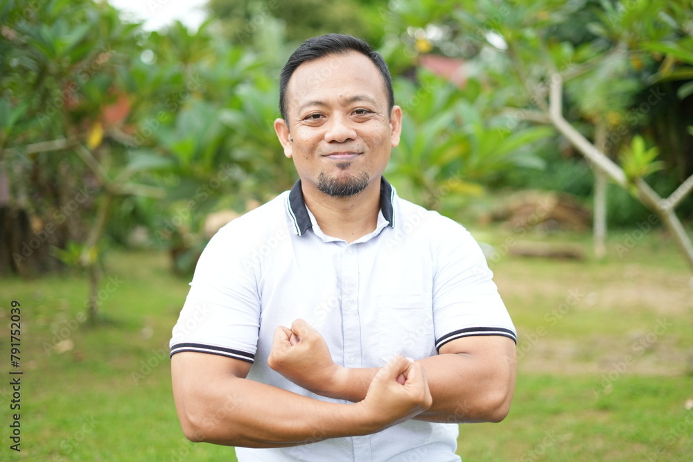 Asian male model wearing white shirt is sitting with facial expression in nature Asian male model wearing white shirt is sitting with facial expression in nature