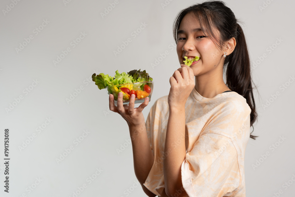 Portrait of a happy playful Asian girl eating fresh salad from a glass bowl after workout at home. Young lady Enjoying Healthy Nutrition And Organic Food, Having Vegetarian Meal Portrait of a happy playful Asian girl eating fresh salad from a glass bowl after workout at home. Young lady Enjoying Healthy Nutrition And Organic Food, Having Vegetarian Meal