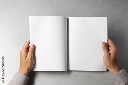 Fototapeta Naklejka Na Ścianę i Meble -  Man holding blank book at light grey table, top view. Mockup for design