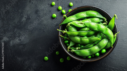 Green Edamame soybeans and green peas on dark rustic background. Healthy food cooking concept. Top view.