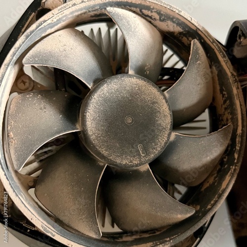 A detailed shot of a grimy metal computer fan resting on a clean white tabletop, reminiscent of automotive tire components like alloy wheels, rims, and hubcaps