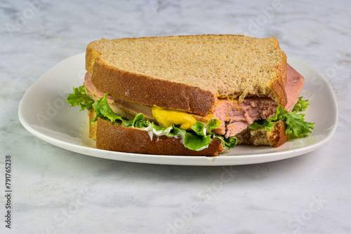 bologna sandwich  with mustard and lettuce