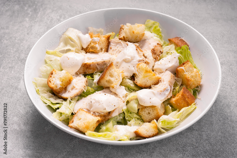 Chicken Caesar Salad in a Bowl with Parmesan Cheese, Dressing and Croutons Chicken Caesar Salad in a Bowl with Parmesan Cheese, Dressing and Croutons