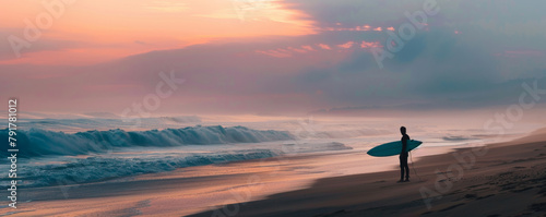 Surfer standing on beach at sunrise with dramatic waves