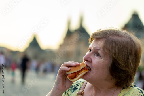 Woman on the street eating a hot dog