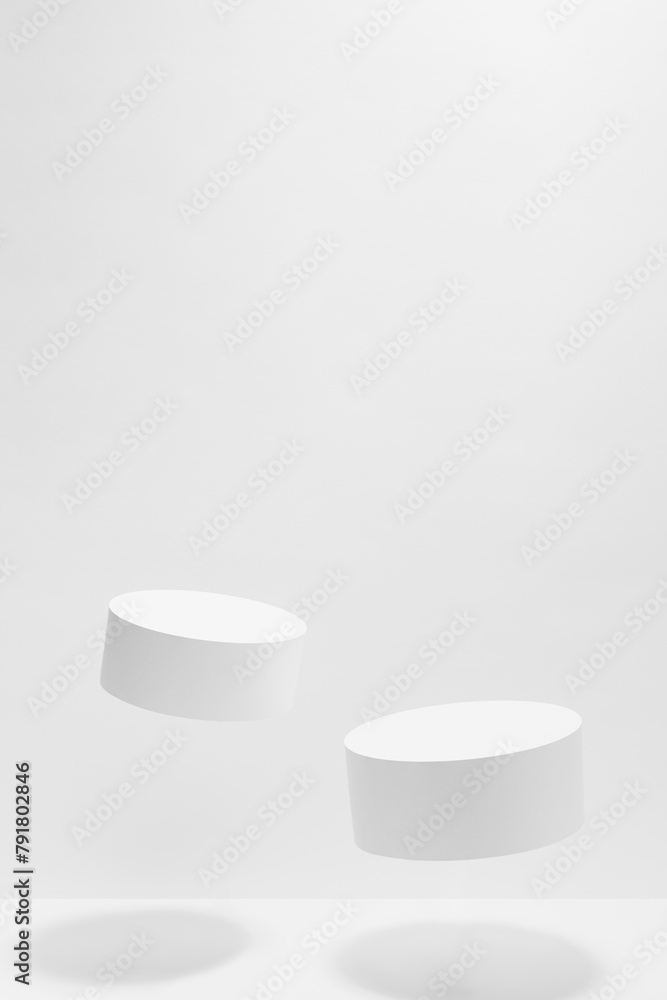 Set of two tilt round white podiums mockup for cosmetic products, levitate in hard light, shadow on white background. Scene for presentation products, gifts, advertising, design in modern style. Set of two tilt round white podiums mockup for cosmetic products, levitate in hard light, shadow on white background. Scene for presentation products, gifts, advertising, design in modern style.