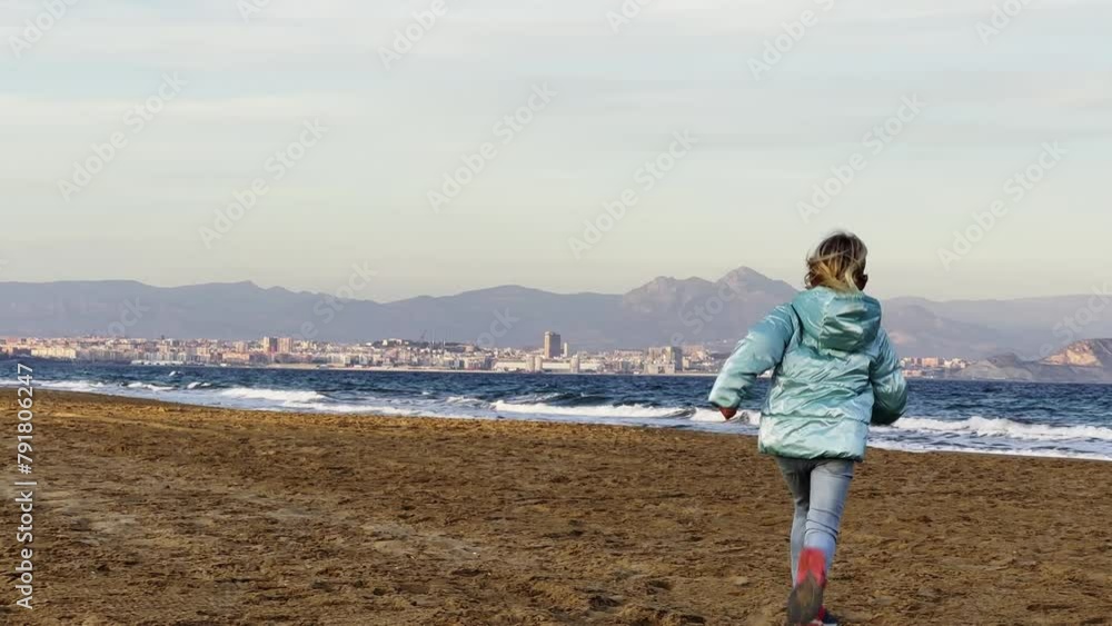 Beautiful girl running at sand beach towards the winter sea. Slow motion Beautiful girl running at sand beach towards the winter sea. Slow motion