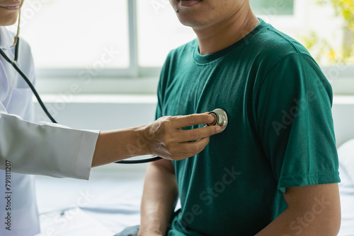 Doctor uses stethoscope to diagnose heart on patient in exam room at hospital, physical exam, medicine and healthcare Checking the heart rate of an adult male patient at a hospital consultation.