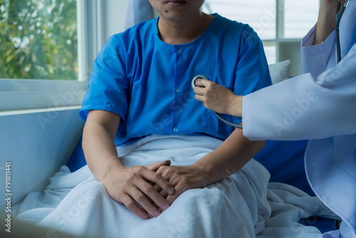 Male patient of Asian descent in bed receives good news from doctor about his recovery in hospital, health, medical and insurance concept.