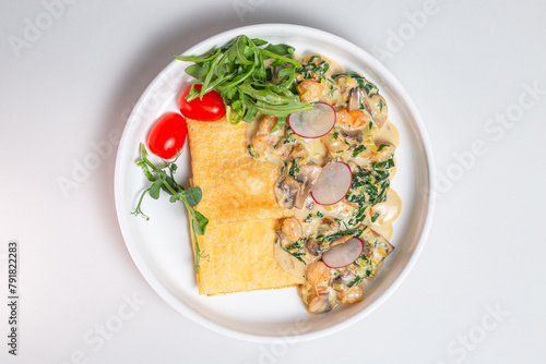 Top view Savory crepe with creamy mushroom sauce and fresh greens on a white plate