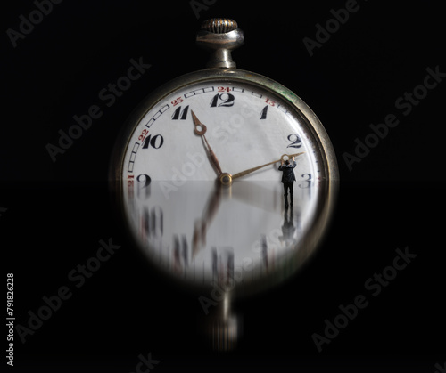 Bussiness man in suit holding clock hand on reflection surface. Stop time concept, deadline