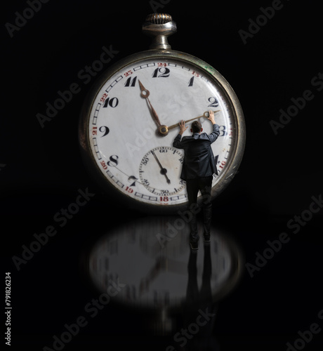 Bussiness man in suit holding clock hand on reflection surface. Stop time concept, deadline
