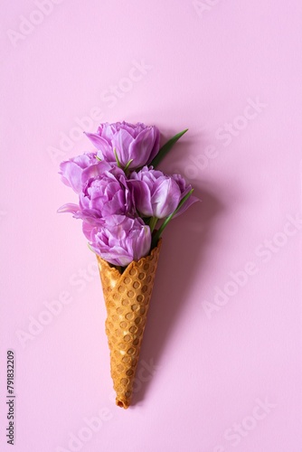 Wafer cone with tulips on pink background. Flower ice cream, spring concept with first flowers.