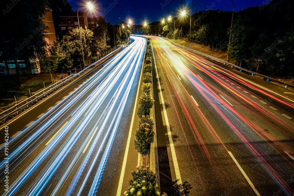 Traces of vehicle lights driving on a highway illuminated by streetlights