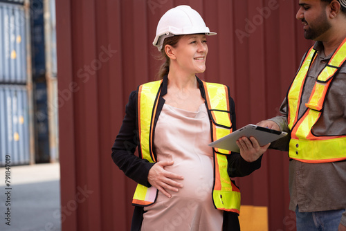 Middle east logistic worker foreman working with caucasian logistic engineer pregnant woman at container site	