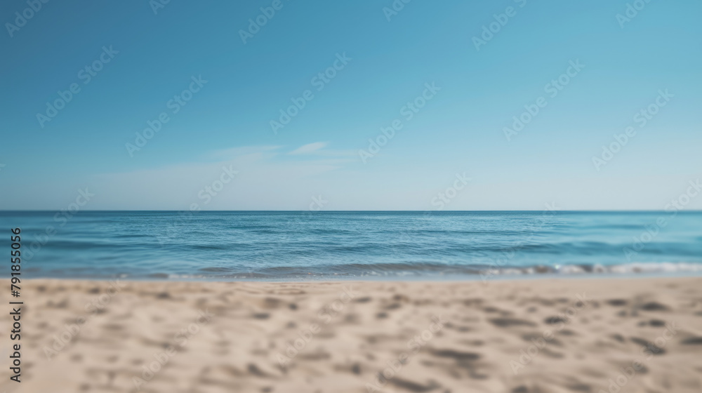 Simple, blurry background of a sandy beach and calm sea.