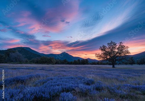 Twilight casts a spell over a serene landscape, where a solitary tree stands guard over a meadow of blue wildflowers under a painted sky.