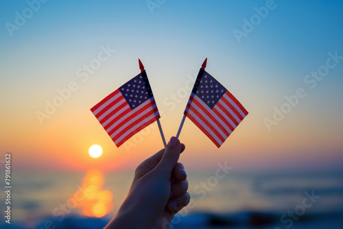 Two American flags held aloft against a soft sunrise over a serene sea, evoking feelings of pride and freedom in a tranquil setting.