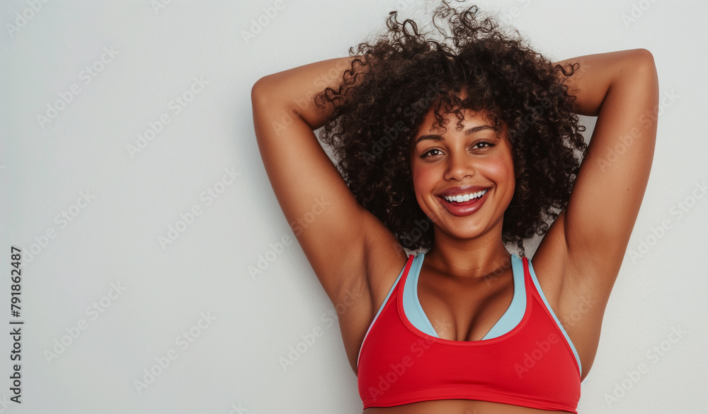 A captivating young athlete with a dazzling smile and curly hair relaxes in a red and blue sports top, reflecting a moment of joy and confidence in her fitness journey. A captivating young athlete with a dazzling smile and curly hair relaxes in a red and blue sports top, reflecting a moment of joy and confidence in her fitness journey.