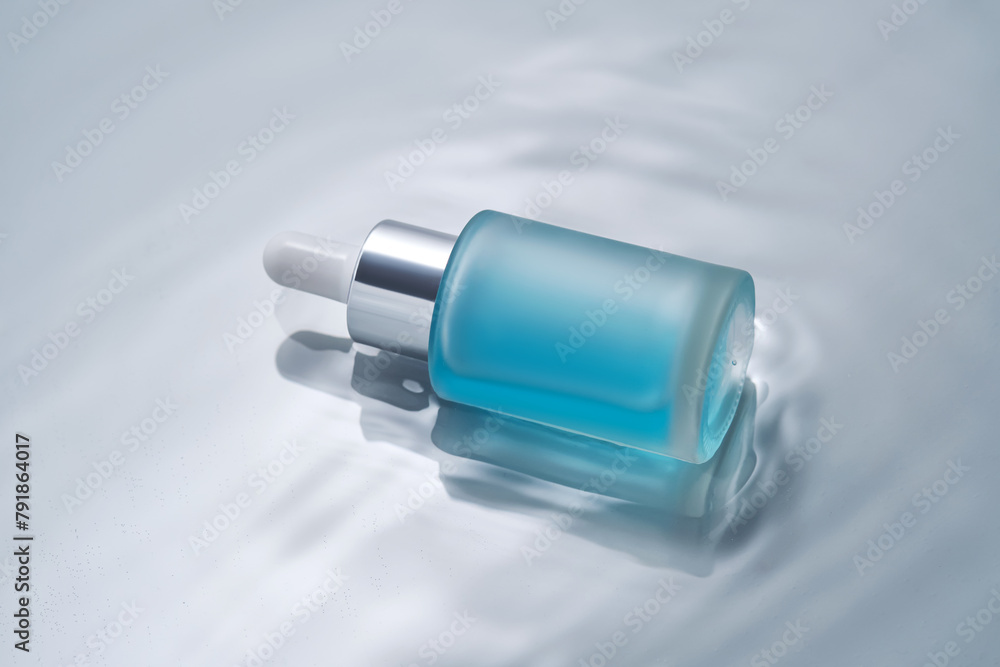Bottles of cosmetics with a dropper in water on a blue background. Bottles of cosmetics with a dropper in water on a blue background.