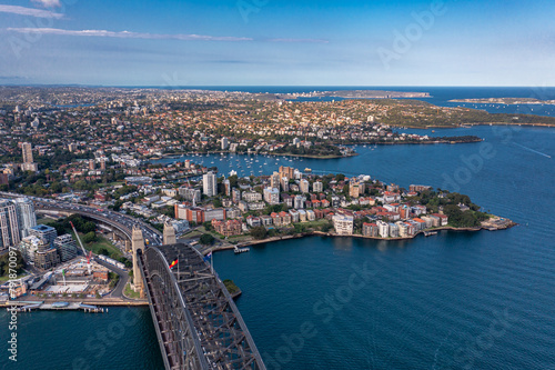 Aerial view along the Sydney Arch Bridge across the Tasman Sea of the city's modern buildings.