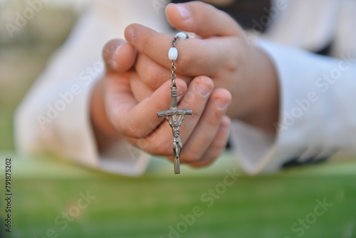 Hands of a Boy praying the rosary holding ,hands folded in prayer