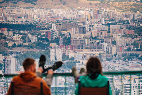 Two people sitting at Mtatsminda park, over the soviet era buildings of Tbilisi, Georgia