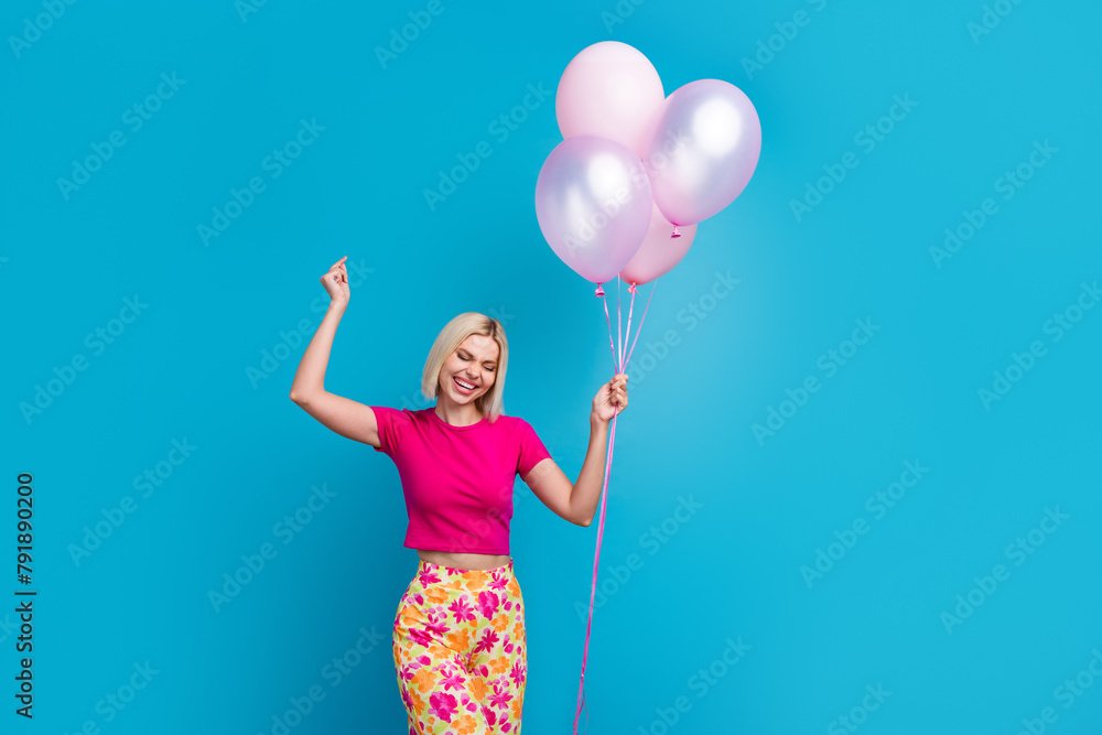 Photo portrait of attractive young woman hold dancing air balloons dressed stylish pink clothes isolated on blue color background Photo portrait of attractive young woman hold dancing air balloons dressed stylish pink clothes isolated on blue color background