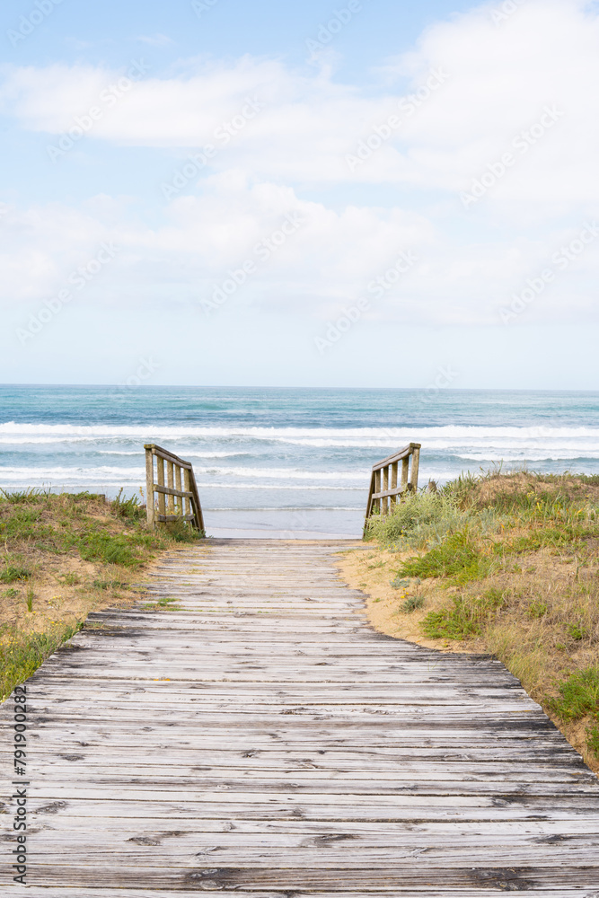 Wooden walkway to reach the beach, sea in the background of the image.