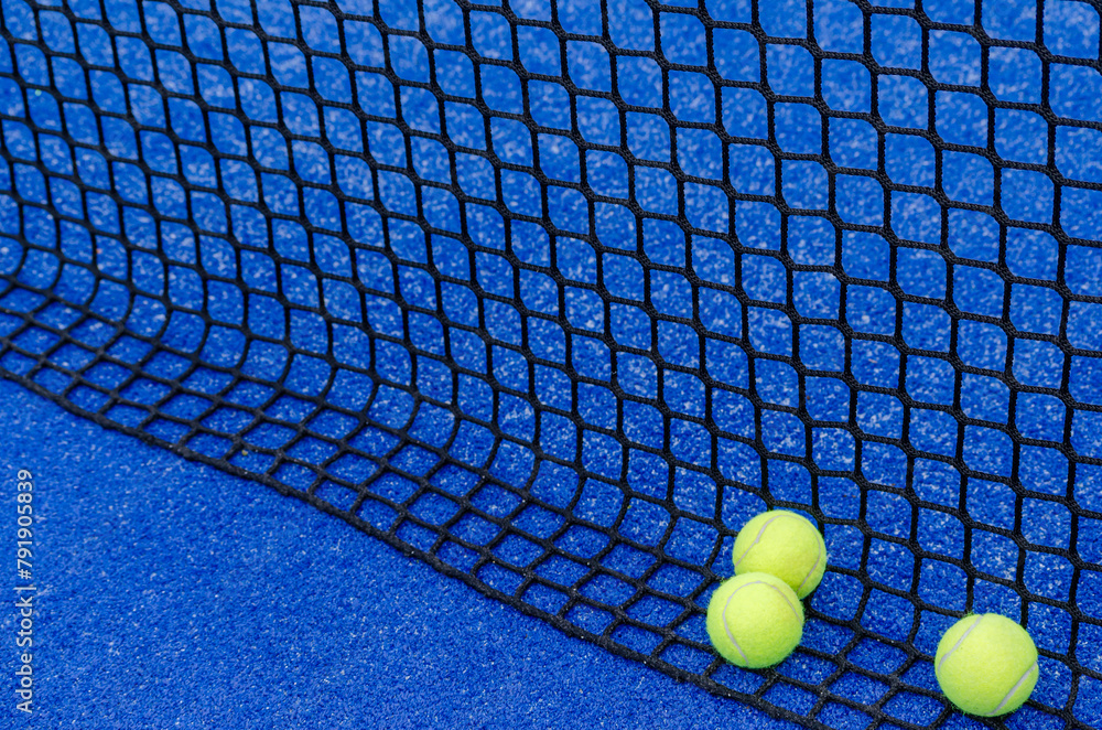 balls next to a paddle tennis court net, racket sports