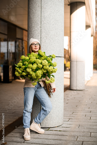 Voluminous bouquet of fresh flowers in a hands of girl in glasses