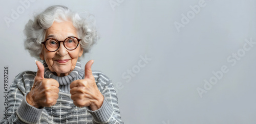 Elderly woman giving thumbs up on a gray background