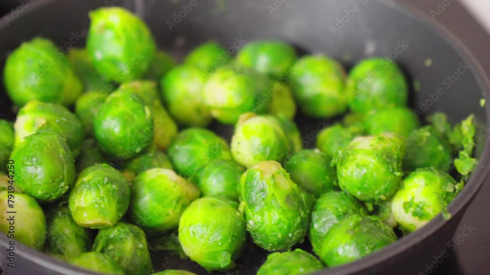 Green brussels sprouts sizzles and simmers on a stove. Selective focus Green brussels sprouts sizzles and simmers on a stove. Selective focus