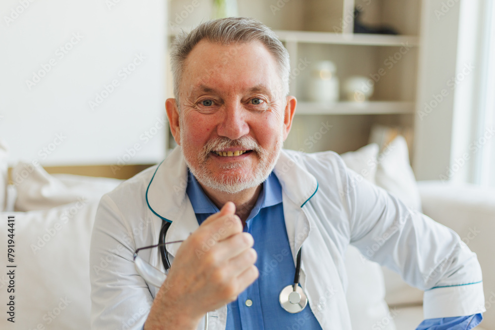 Mature senior male doctor in medical uniform smiling looking at camera in hospital. General practitioner GP therapist professional healthcare expert in clinic. Healthcare concept