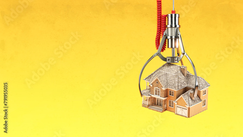 Choosing real estate and mortgage concept.  Machine  claw with house on yellow background.