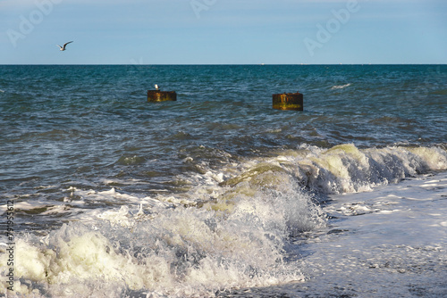 The power of water on the sea surf. Splashes of sea waves. Large waves that occur during stormy weather break against the concrete four-legged supports of the breakwater. 