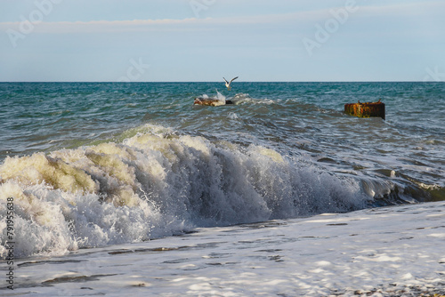 Sea surf on the beach. The power of water on the sea surf. Splashes of sea waves. Large waves that occur during stormy weather break against the concrete four-legged supports of the breakwater.